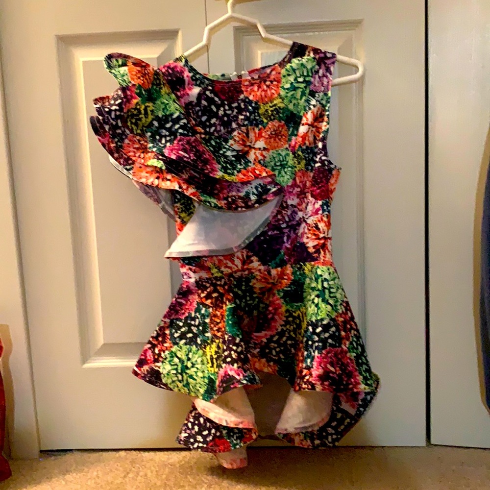 Never worn, durable cotton/poly floral, ruffle bottom and one ruffle sleeve. Zip